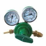 Green oxygen gas regulator with dual pressure gauges and brass fittings, designed for industrial use.